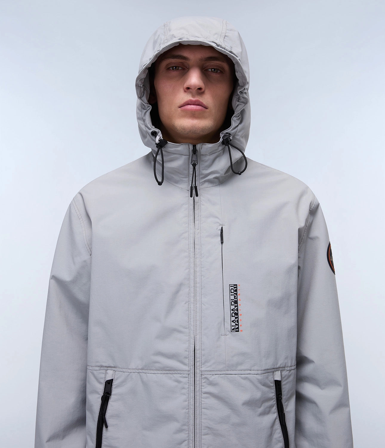 Napapijri Tundra Jacket in grey, lightweight outdoor jacket with hood, visible zippers, and durable fabric for outdoor wear.