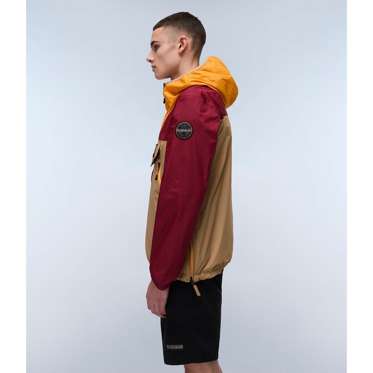 Napapijri Rainforest jacket in beige, red, and yellow with a hood and front zipper, stylish outdoor wear for men or women.