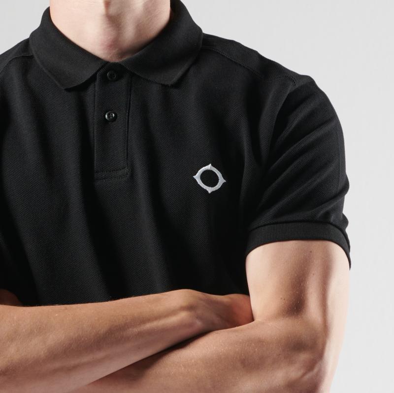 Black MA.Strum pique polo shirt displayed flat with collar and buttons, showcasing its classic design and textured fabric.