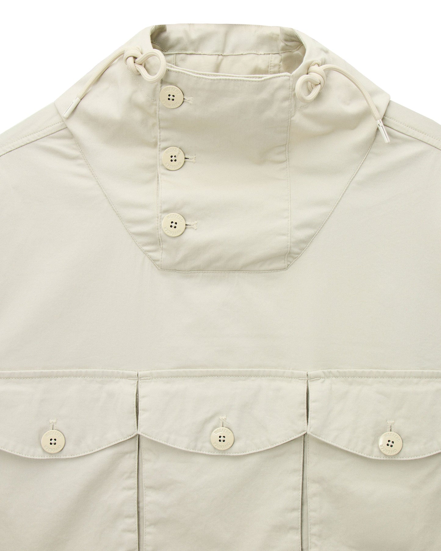 Weekend Offender Kovags over-top cement-colored jacket with front pockets and adjustable hood, displayed on a hanger.
